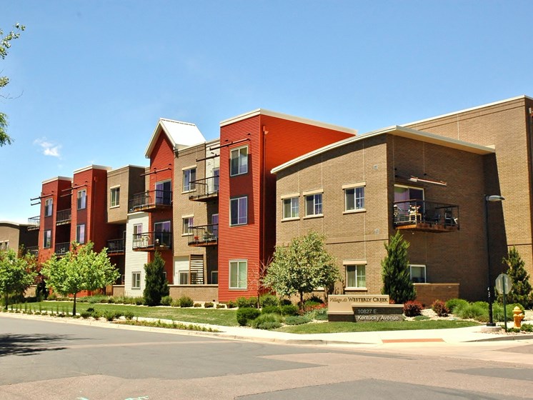 Exterior shot of VWC1, brown brick, orange siding, patios, landscaped with trees and grass